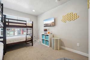 Bedroom featuring light colored carpet and a textured ceiling