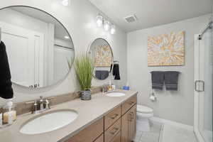 Full bathroom with double vanity, light tile patterned floors, and a stall shower