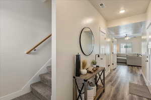 Corridor with a textured ceiling, wood finished floors, and stairway