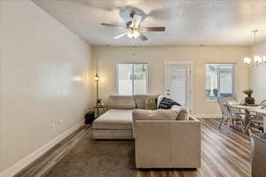 Living area with wood finished floors, a textured ceiling, healthy amount of natural light, and a chandelier