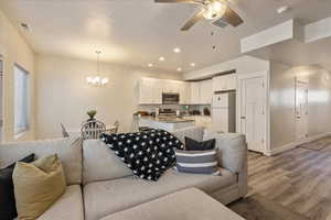 Living room with recessed lighting, ceiling fan, a chandelier, wood finished floors, and a textured ceiling