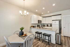 Kitchen featuring light stone counters, white cabinets, stainless steel appliances, recessed lighting, and pendant lighting