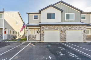 View of front of home with stone siding, board and batten siding, driveway, and a garage