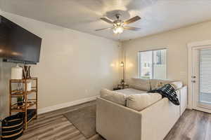 Living room featuring a textured ceiling, wood finished floors, and a ceiling fan