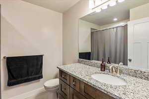 Bathroom featuring a shower with shower curtain, vanity, and a textured ceiling