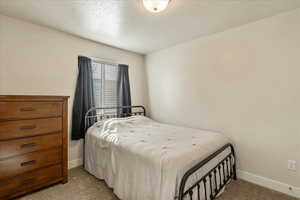 Carpeted bedroom with a textured ceiling and baseboards