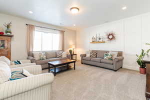 Carpeted living area with a decorative wall and recessed lighting