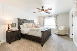 Bedroom with light colored carpet, ceiling fan, and wallpapered walls