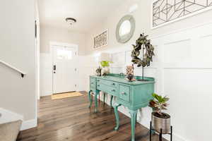 Entrance foyer with stairs, a decorative wall, a wainscoted wall, and wood finished floors