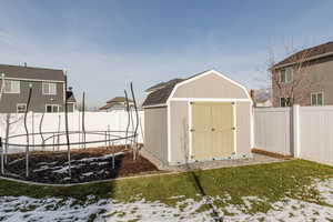 View of shed featuring a trampoline and a fenced backyard