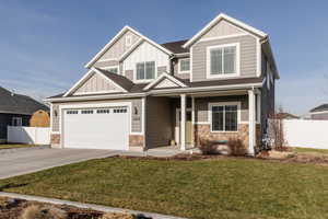 Craftsman inspired home with board and batten siding, stone siding, concrete driveway, and a garage