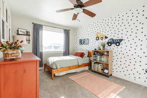 Bedroom with wallpapered walls, a ceiling fan, and light carpet