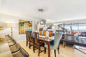 Dining space with crown molding, a chandelier, and light tile patterned floors