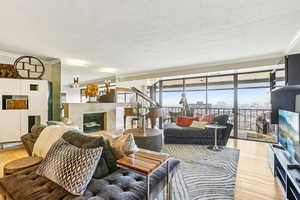 Living room with ornamental molding, a premium fireplace, light wood finished floors, and a textured ceiling