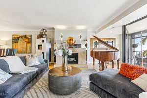 Living room with a fireplace, crown molding, wood finished floors, and a textured ceiling