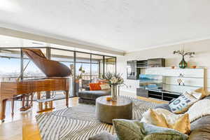 Living room featuring crown molding, plenty of natural light, expansive windows, wood finished floors, and a textured ceiling