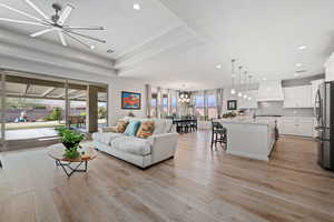 Living area with a textured ceiling, light wood finished floors, a ceiling fan, a chandelier, and recessed lighting