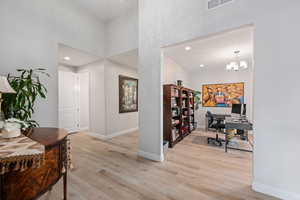 Office area with light wood-style floors, recessed lighting, and a chandelier