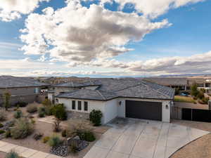 View of front of house with stucco siding, a garage, stone siding, driveway, and a residential view
