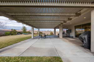 View of patio with grilling area and a pergola