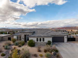 Prairie-style house with stucco siding, stone siding, a garage, concrete driveway, and a residential view