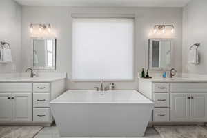 Full bath featuring two vanities, plenty of natural light, and a freestanding bath