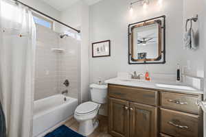 Full bath with shower / tub combo with curtain, vanity, and wood finished floors