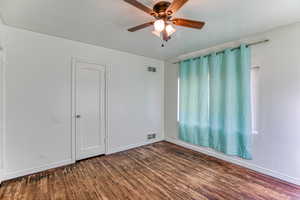 Empty room with dark wood-type flooring and a ceiling fan