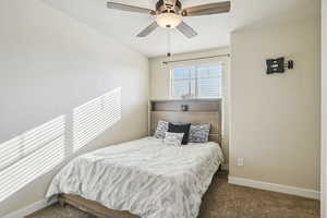 Carpeted bedroom featuring ceiling fan and a textured ceiling