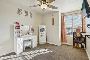 Home office with light colored carpet and ceiling fan