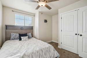 Bedroom featuring dark colored carpet, a textured ceiling, a ceiling fan, and a closet