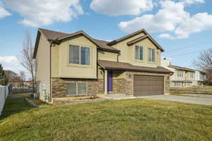 View of front of property with stucco siding, stone siding, concrete driveway, and a garage