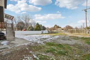 Snowy yard with a patio area, a wooden deck, and stairway