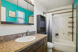 Bathroom featuring a textured ceiling, shower / bath combo with shower curtain, and vanity