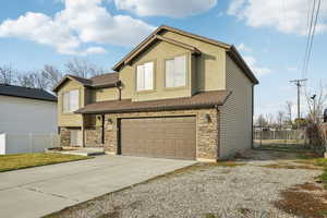 Traditional home featuring stone siding, concrete driveway, a garage, and stucco siding