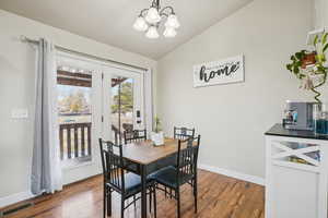 Dining room with lofted ceiling, a chandelier, and wood-type flooring