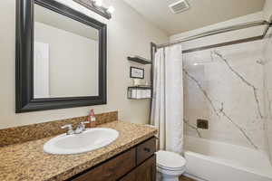 Full bathroom with a textured ceiling, shower / bath combination with curtain, and vanity