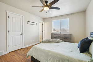 Bedroom featuring a textured ceiling, hardwood / wood-style flooring, and a ceiling fan