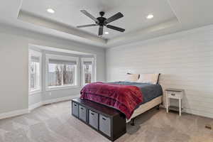 Primary suite with tray ceiling, canned lighting, ceiling fan and bay window