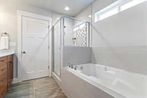 Separate tub and shower, walk-in closet, and quartz-topped vanity