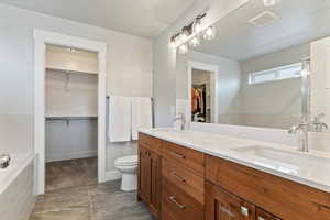 Separate tub and shower, walk-in closet, and quartz-topped vanity