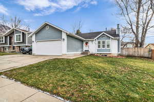 View of front of home with a chimney, driveway, a front lawn, and an attached garage