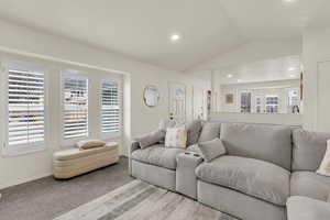 Carpeted living area featuring vaulted ceiling and recessed lighting