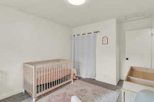 Bedroom featuring a nursery area, carpet flooring, and attic access