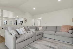 Living room with recessed lighting, lofted ceiling, and light wood-style floors