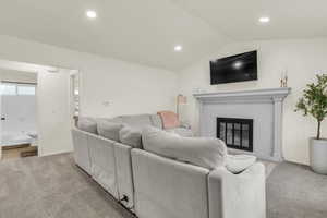 Living room featuring light carpet, a fireplace, vaulted ceiling, and recessed lighting