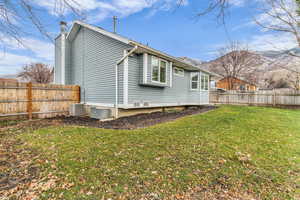 Rear view of house with a fenced backyard, a chimney, and a mountain view