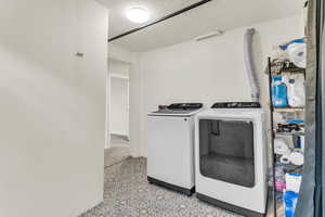 Laundry room with a textured ceiling, independent washer and dryer, and light flooring