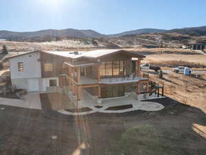 View of front of home with a deck with mountain view, stone siding, and driveway
