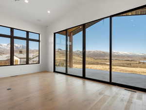 Spare room with a mountain view, light wood finished floors, vaulted ceiling, and recessed lighting